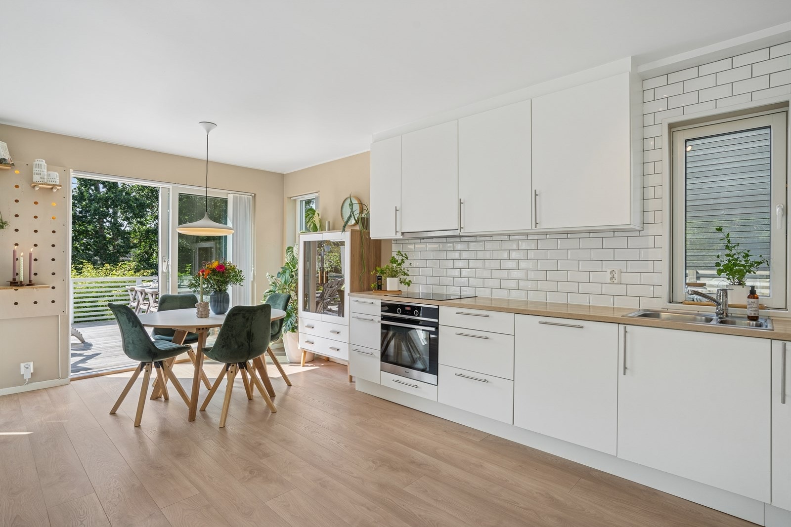 Kjøkkenet har en pen og tidløs innredning med hvite, glatte fronter, laminert benkeplate og nedfelt vask i rustfritt stål. Galleribilde