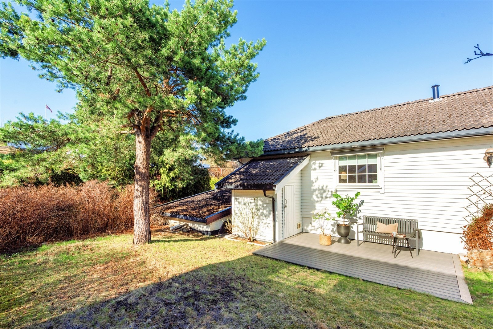 Eiendommen har en grønn og trivelig hage med plen, trær og beplantning som skaper en skjermet og koselig atmosfære. Her er det gode muligheter for å nyte rolige dager utendørs i hyggelige omgivelser. Grantreet er felt siden bildet ble tatt. Galleribilde