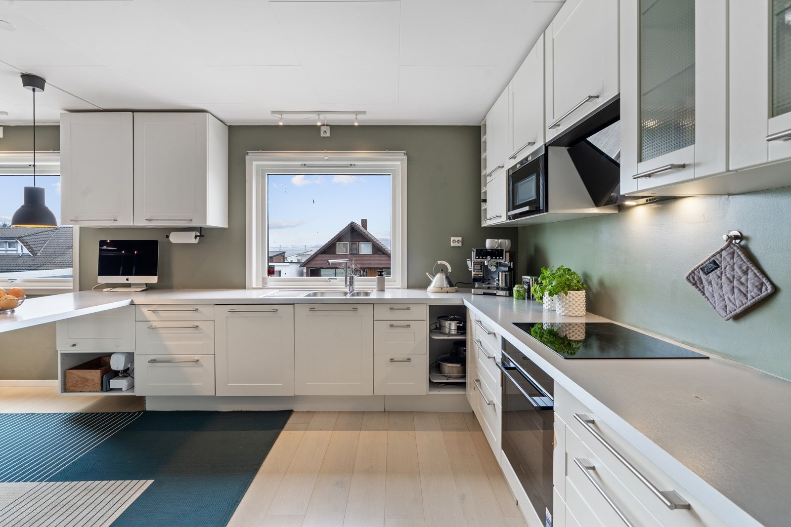 Kjøkken i hvit utførelse og med integrert komfyr, stekeplate og oppvaskmaskin Galleribilde