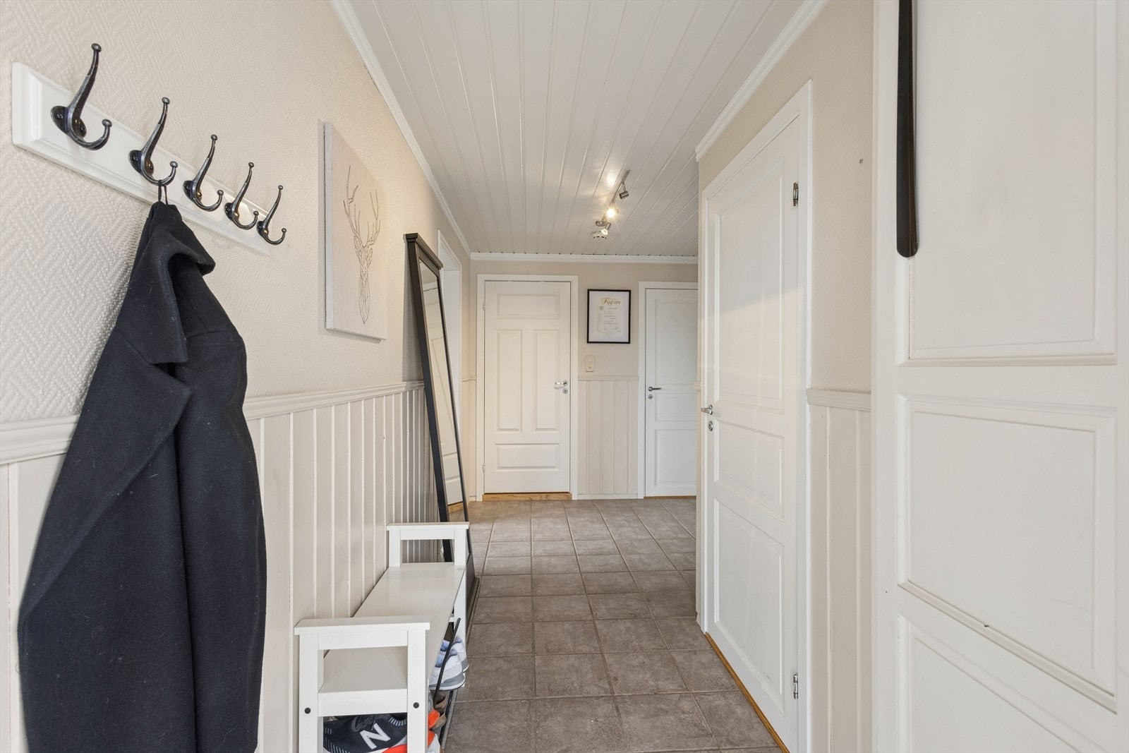 Entréen har flislagt gulv og tilgang til en praktisk bod for oppbevaring. Galleribilde