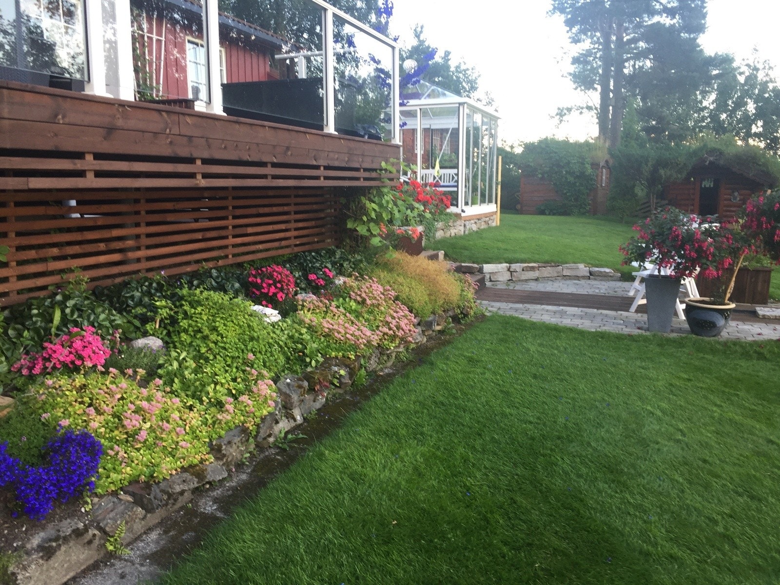 Pent opparbeidet uteområde med grønne plener og beplantede bed. Galleribilde