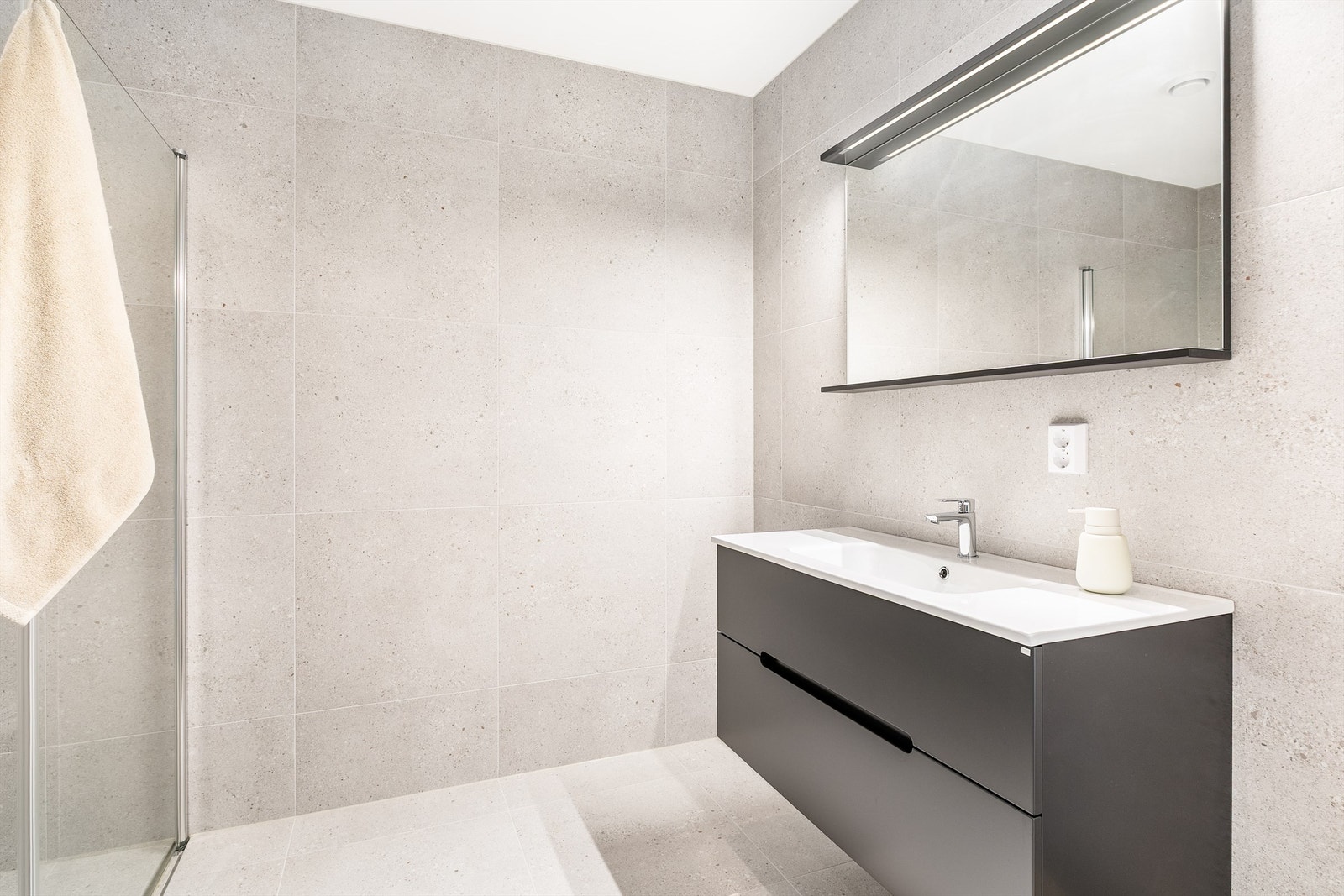 Store terrazzofliser av 60x60 cm. format på både gulvet og veggene gir badet helhet og aktualitet. Galleribilde