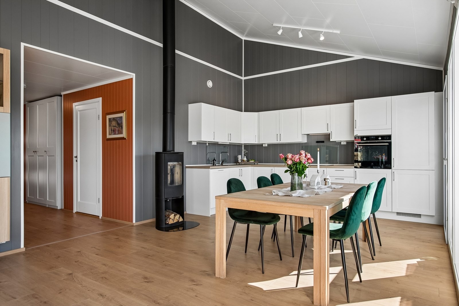Moderne kjøkken med profilerte fronter og integrerte hvitevarer. Peisovnen er sentralt plassert for varme og hygge. Galleribilde