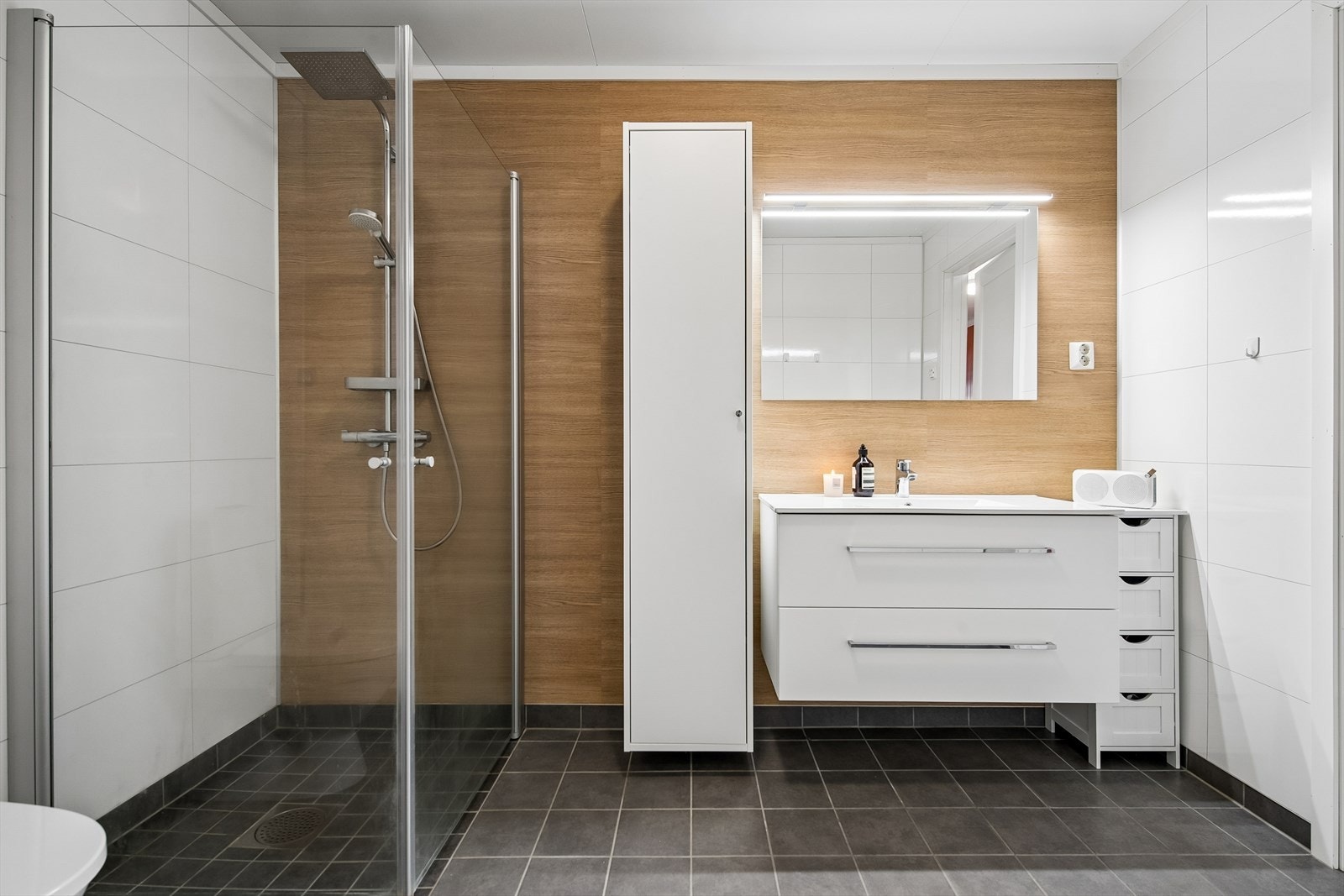 Badet har flislagt gulv med elektriske varmekabler og baderomsplater på veggene. Dusjhjørnet har praktiske, innfellbare vegger. Galleribilde