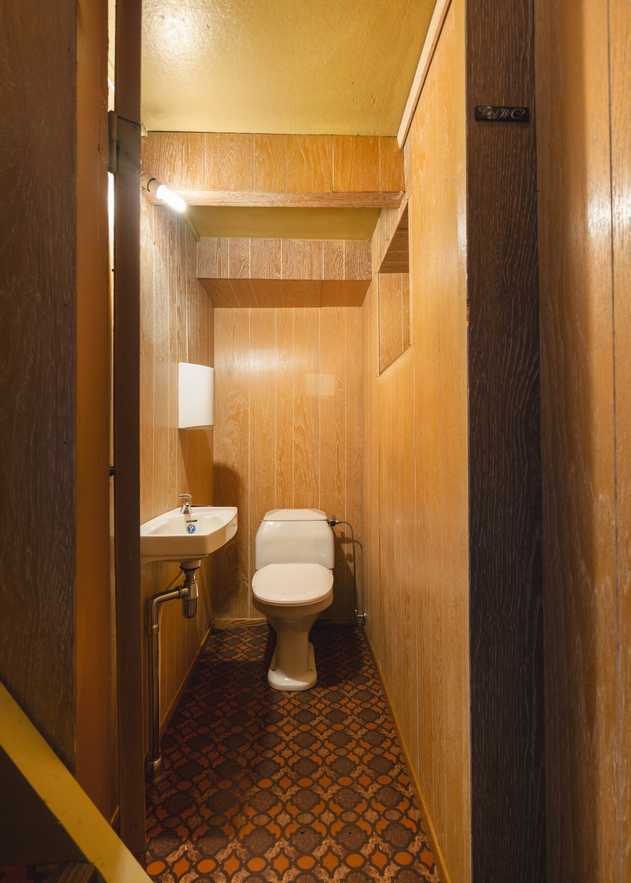 Toalettrom i kjeller med belegg på gulv og finerplater på vegg. Galleribilde