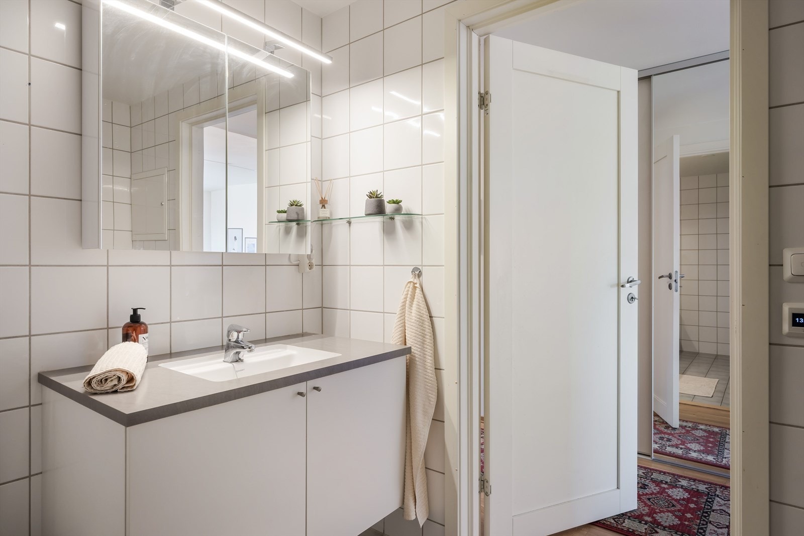 Baderomsinnredningen består av servant med underskap i hvit utførelse og speilskap med lysarmatur. Galleribilde