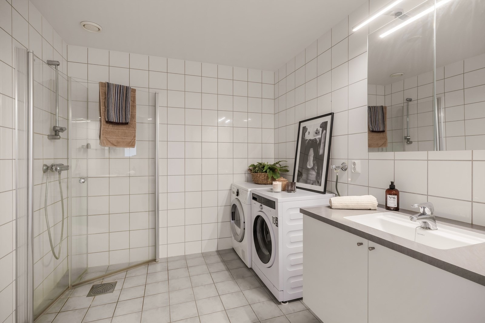 Tidløst innredet baderom kledd med lys flis på gulv og vegg. Varmekabler i gulvet gir en behagelig start på dagen. Galleribilde