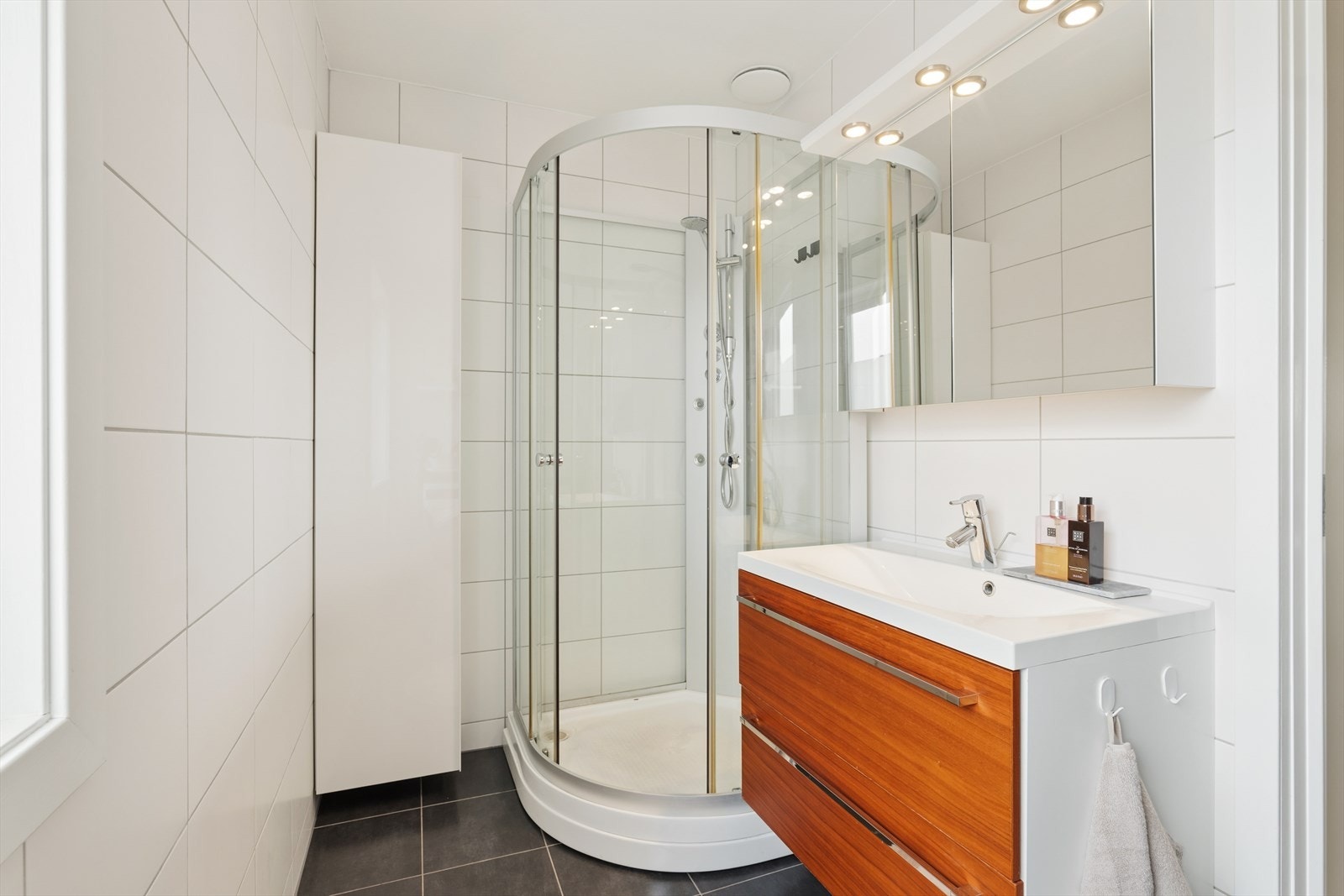 Badet har varmekabler i gulvet og er utstyrt med servant, dusjkabinett og opplegg til vaskemaskin og tørketrommel Galleribilde