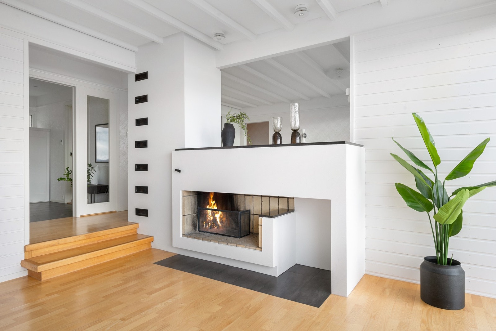 Innbydende overgang fra hall til stue med peis som deler sonene. Galleribilde