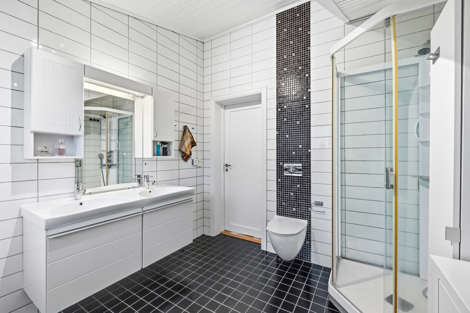 Rommet har mørke gulvfliser med gulvvarme, heldekkende dobbelservant og vegghengt toalett. Galleribilde