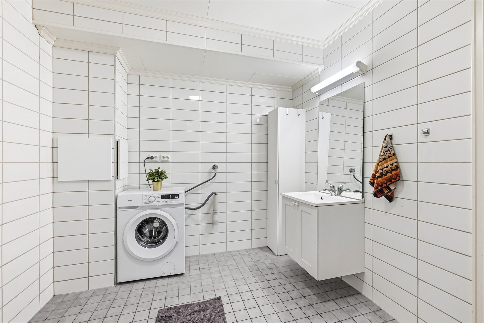 En smart detalj er skittentøyssjakten fra loftsetasjen som ender her på vaskerommet. Galleribilde