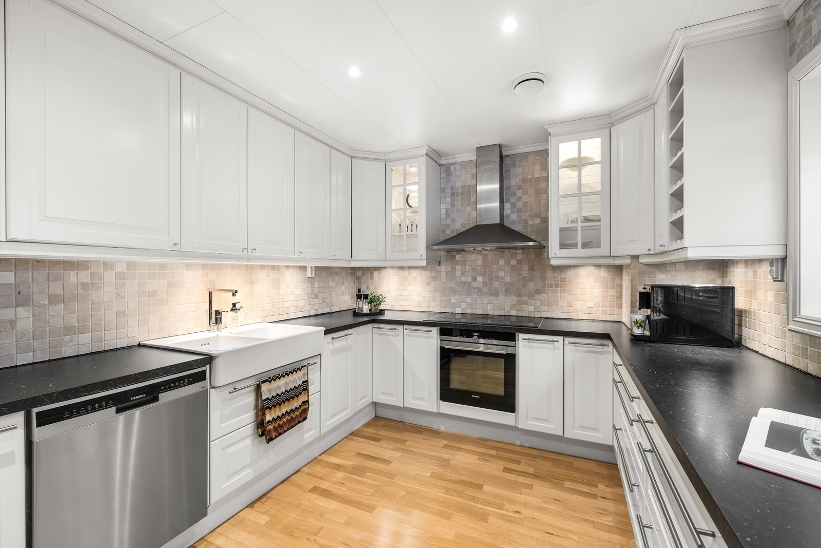 Innredningen har hvite, profilerte fronter og kledelige mosaikkfliser mellom over- og underskap. Galleribilde