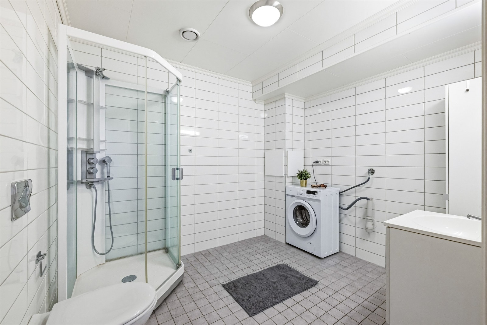 Stort, kombinert bad og vaskerom i underetasjen. Rommet er utstyrt med gulvvarme, dusjkabinett og opplegg for vaskemaskin og tørketrommel. Galleribilde