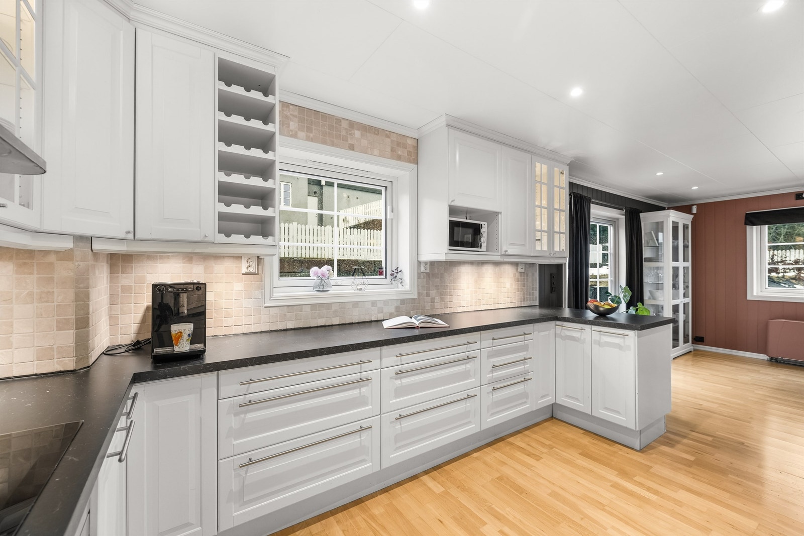 Gjennomtenkte detaljer som vitrineskap med belysning og integrert vinhylle hever inntrykket. Galleribilde