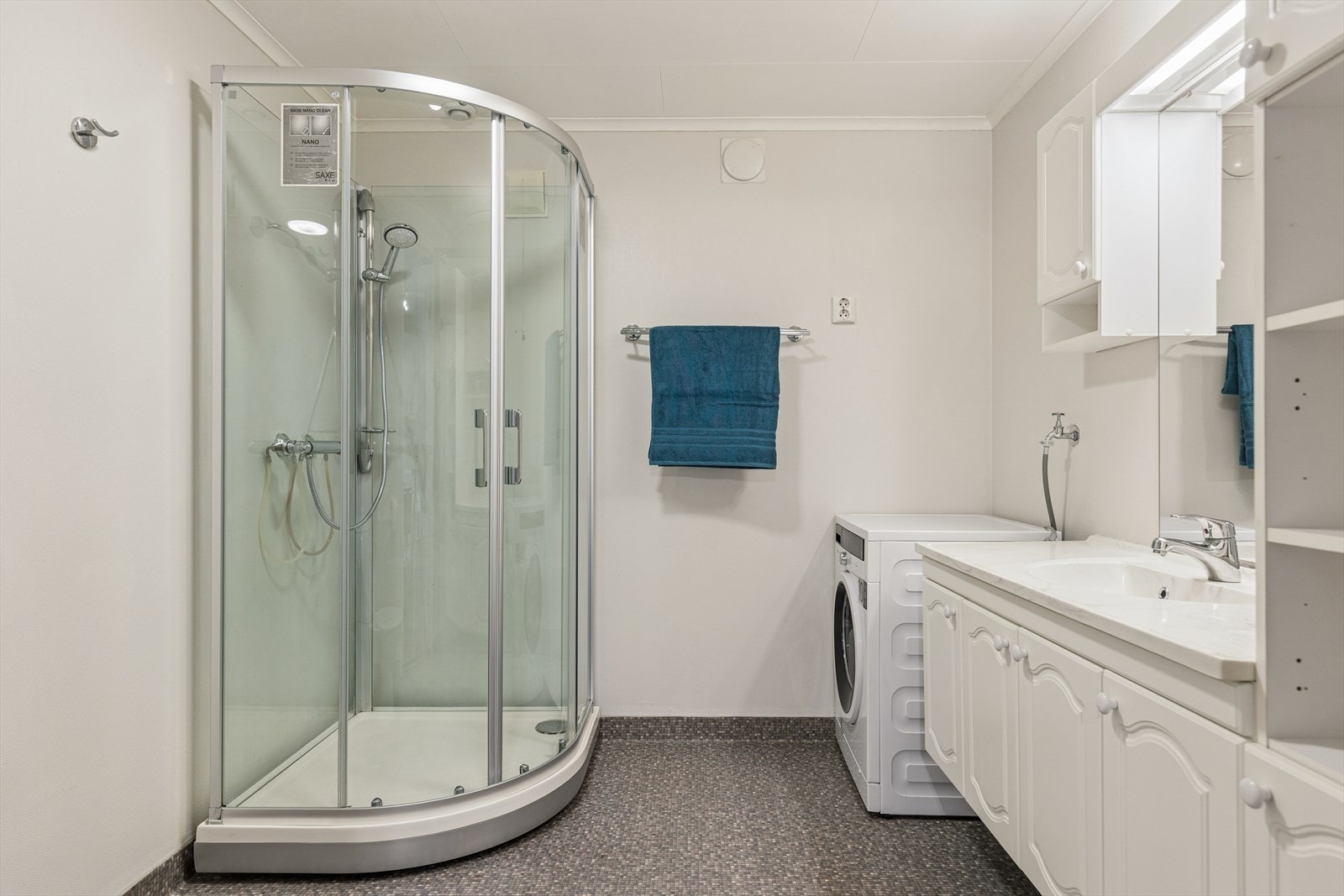 Baderom med vinylbelegg på gulv m/ elektriske varmekabler, veggene har våtromstapet/belegg og taket er malt. Rommet har innredning med nedfelt servant, toalett, dusjkabinett og opplegg for vaskemaskin.
Det er mekanisk avtrekk. Galleribilde