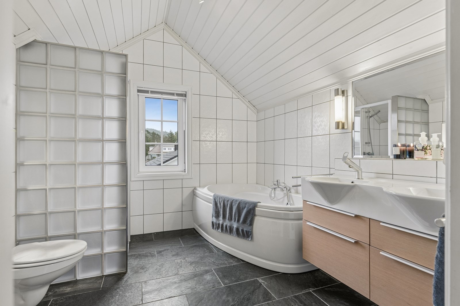 Det andre badet på loft er fra 2011. Badet er helfliset med elektriske varmekabler i gulv. Taket har malt panel. Rommet har innredning med 2 heldekkende servanter, veggmontert toalett, boblebad og dusjvegger/hjørne. Galleribilde