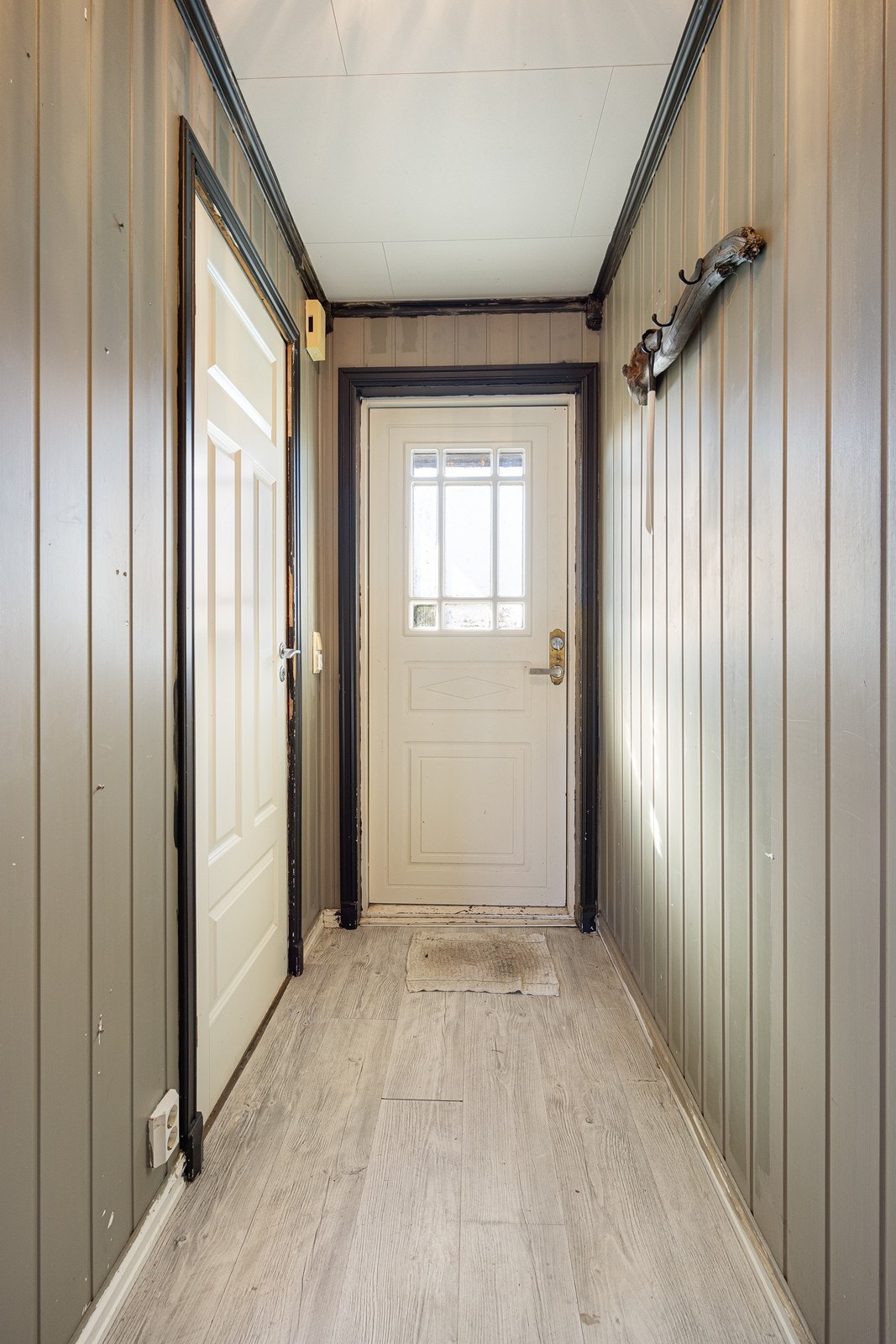 Entreen har gråmalt panel på veggene og lys laminat på gulv med gulvvarme. Galleribilde