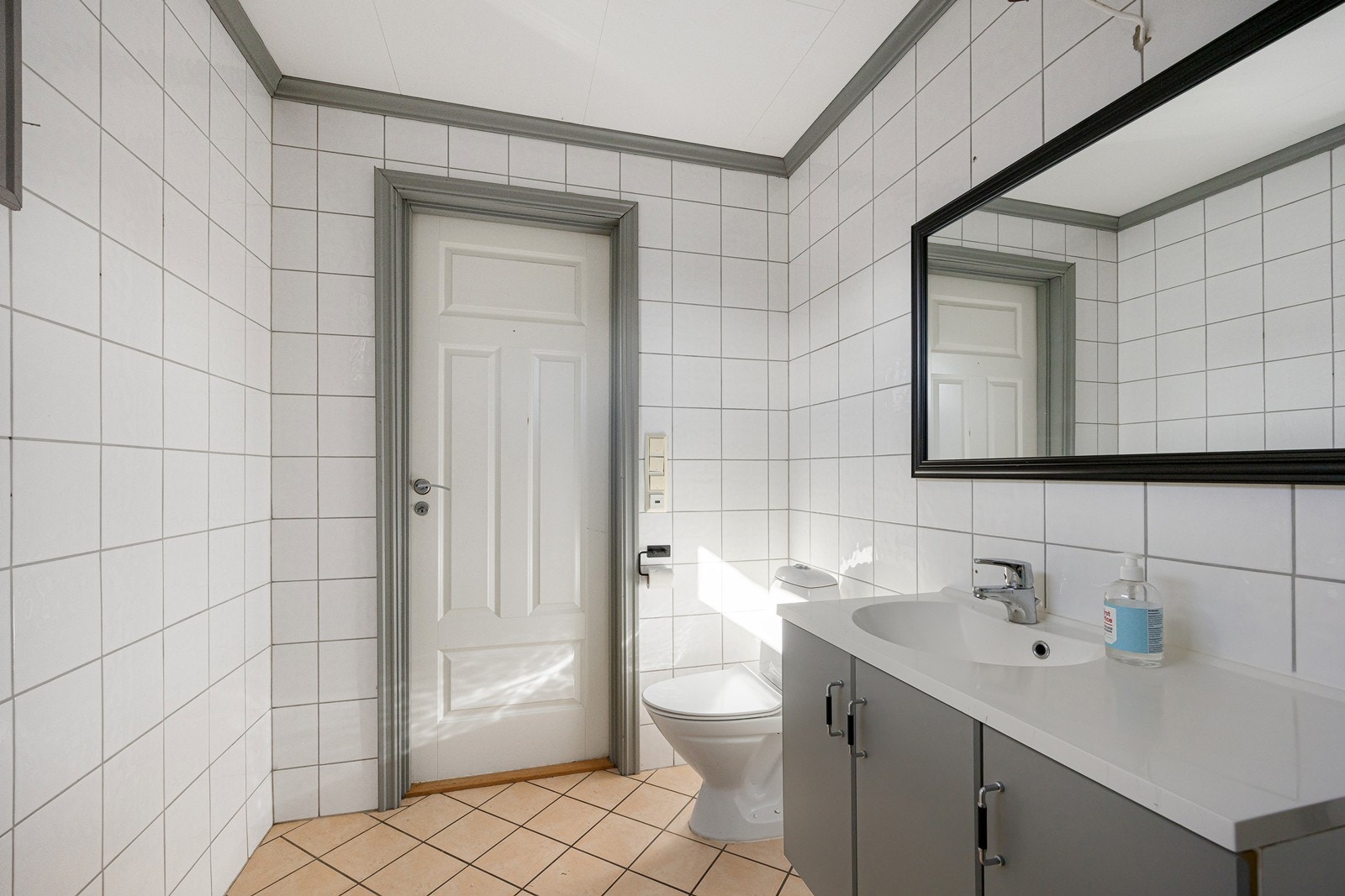 Badet fremstår som praktisk og fint. Her er det hvite fliser på veggene, og på gulvet er det lagt beige fliser over elektrisk gulvvarme. Galleribilde