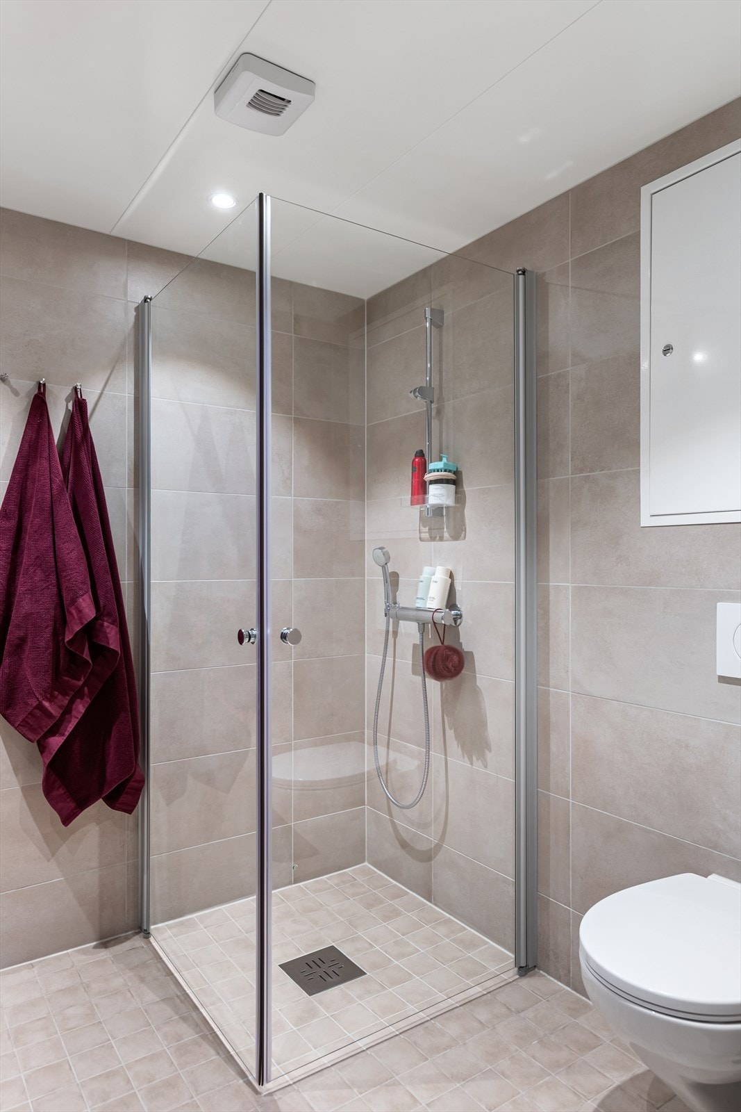 Badet er utstyrt med vegghengt toalett, dusjhjørne med glassdører og downlights i taket. Galleribilde