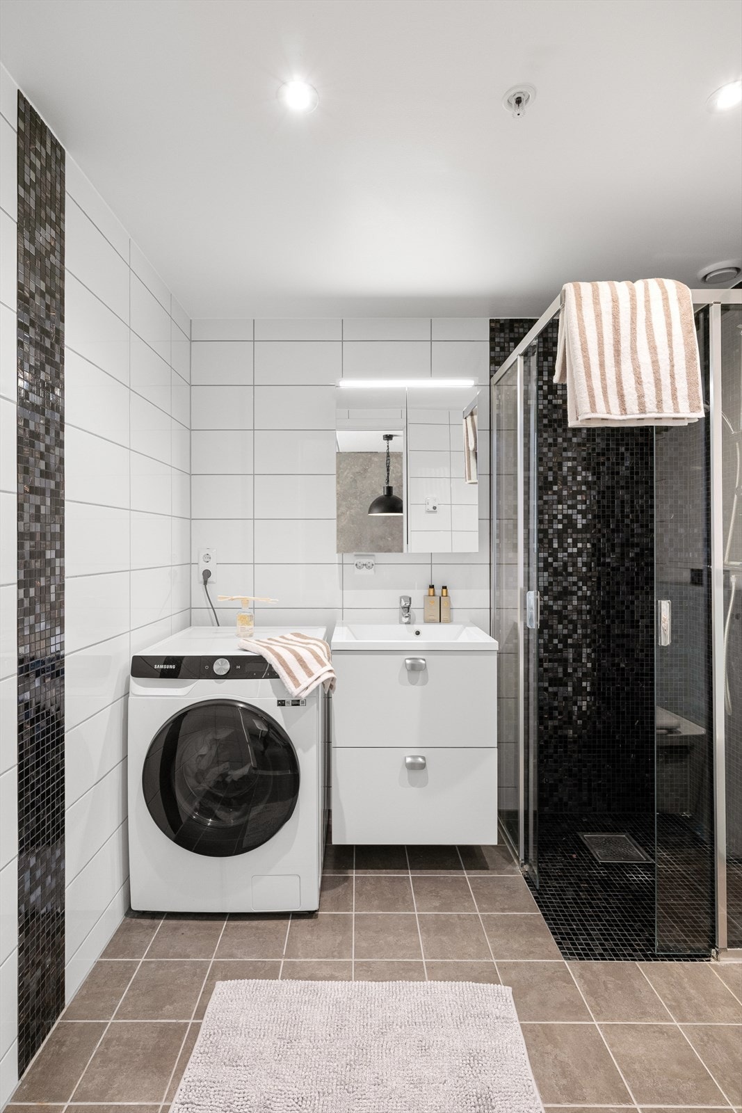 Badet er helfliset med varmekabler i gulvet, og er innredet med nedfelt servant, vegghengt toalett og dusjhjørne. Galleribilde