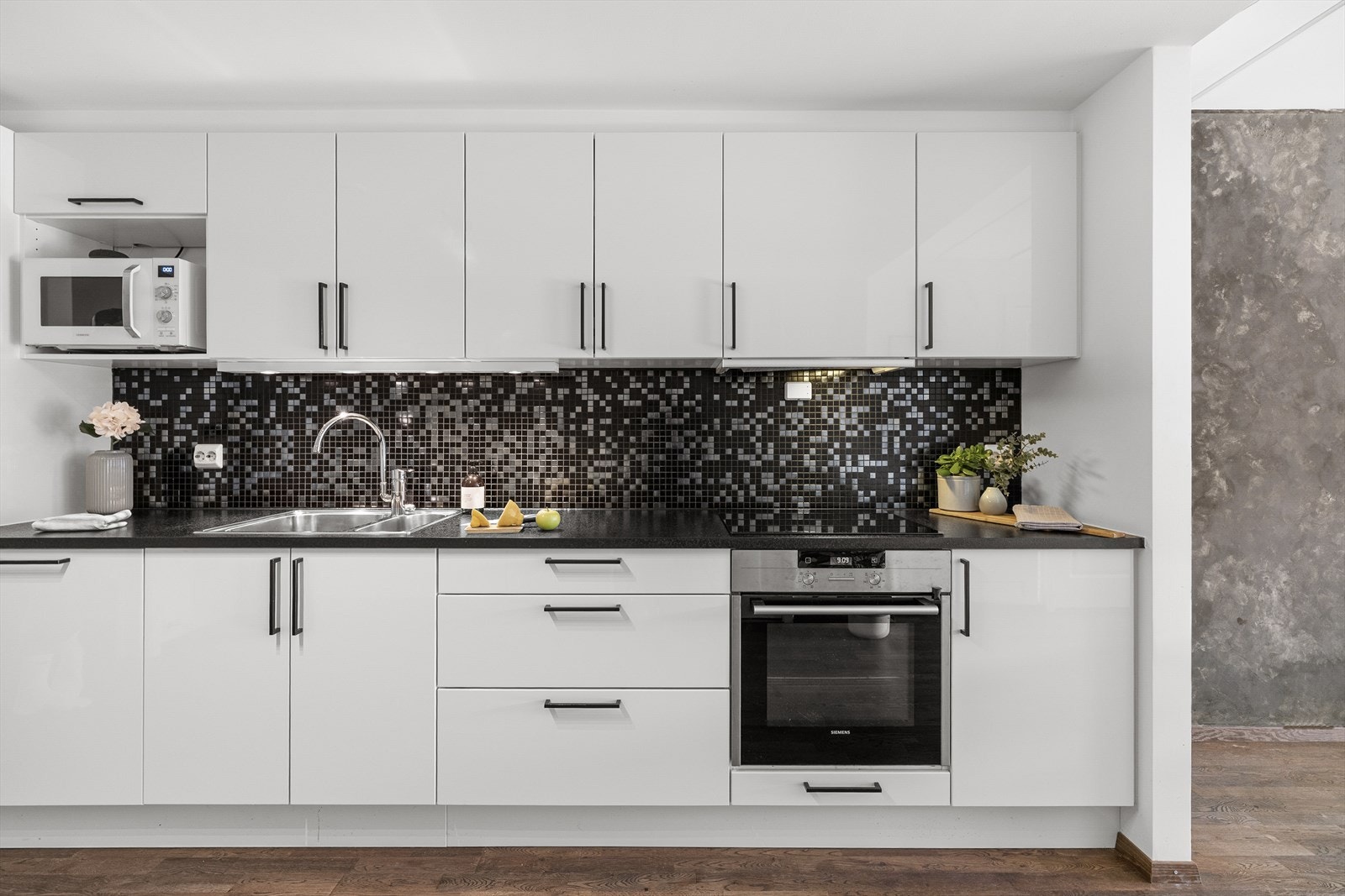 Tidløs kjøkkeninnredning med hvite, glatte fronter kombinert med en benkeplate av laminat. Galleribilde