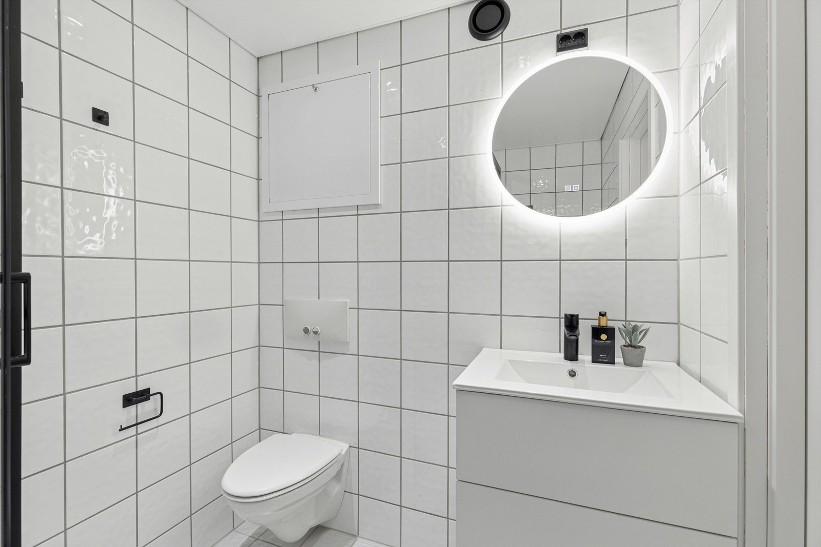 Badet er innredet med nedfelt servant, speil med integrert belysning, veggmontert toalett, dusjkabinett og opplegg for vaskemaskin. Galleribilde