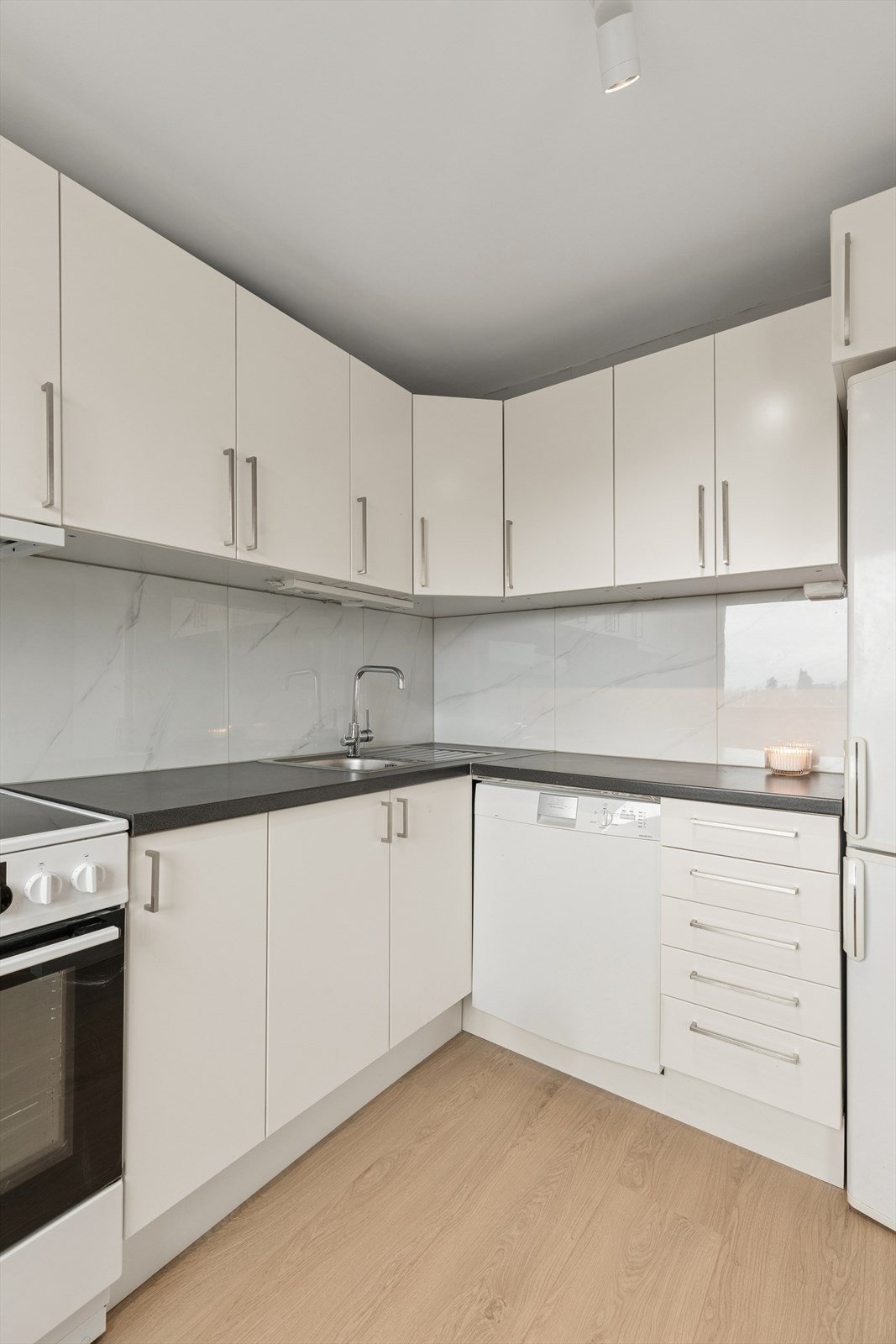 Mellom benkeplate og overskap er veggen flislagt av fagfirma i mars 2026, noe som både løfter uttrykket og gjør renhold enklere. Galleribilde