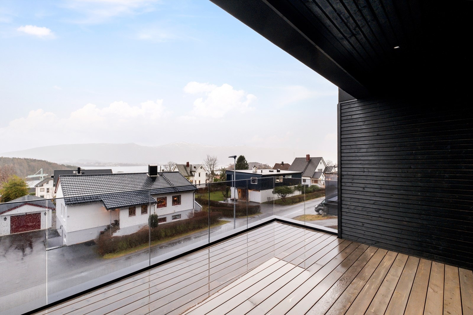 Terrasse mot sør med stilig glassrekkverk og dekke av terrassebord, delvis overbygget med god belysning. Galleribilde