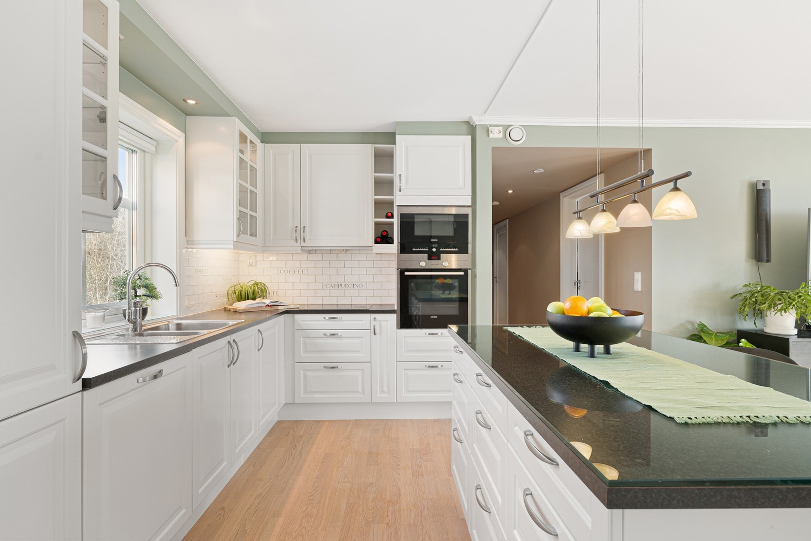 Kjøkkenet har en praktisk barløsning som gir ekstra skap- og benkeplass. Galleribilde