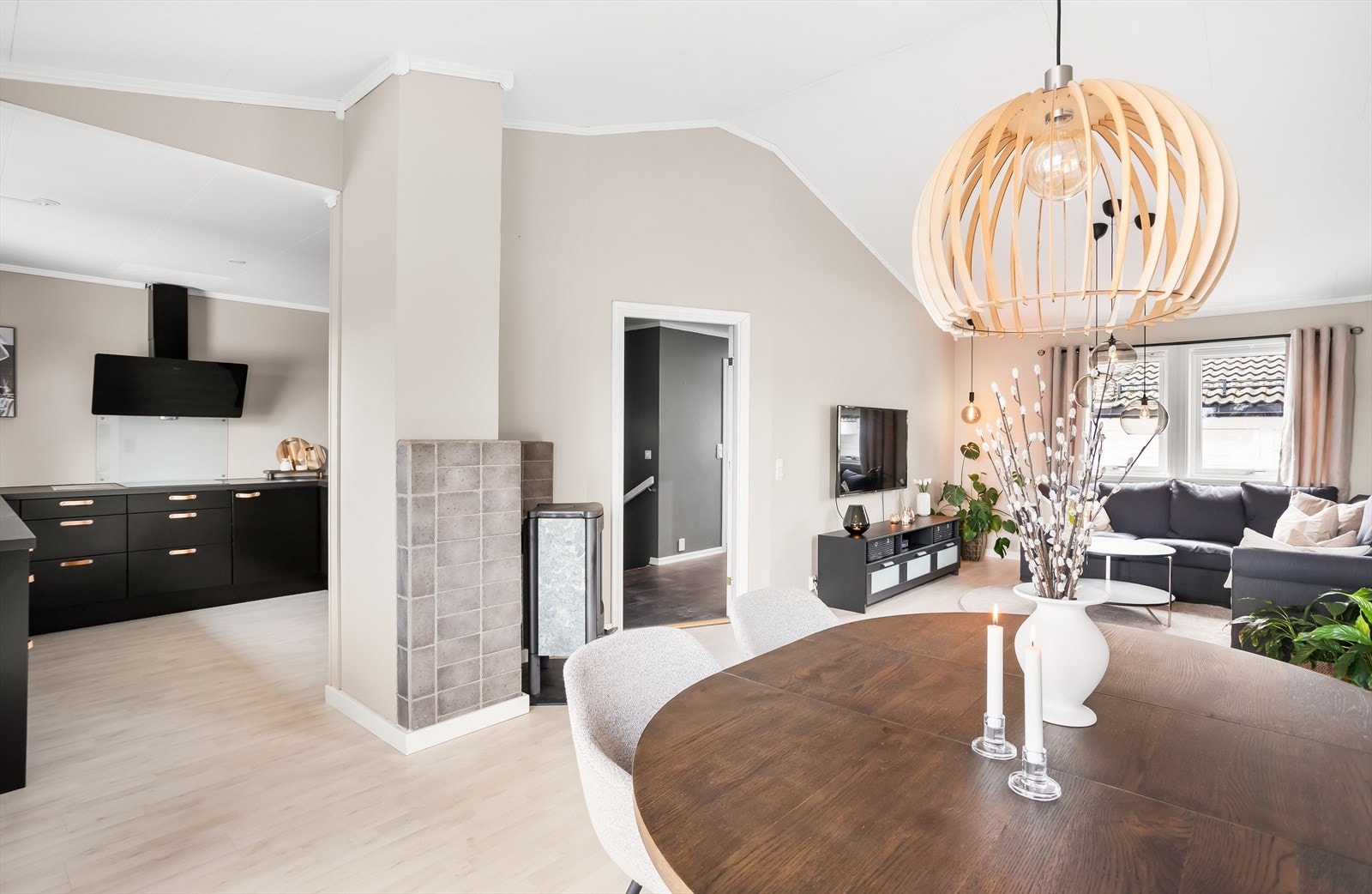 En sosial og åpen løsning mellom stue og kjøkken, med ildstedet som et naturlig midtpunkt. Galleribilde