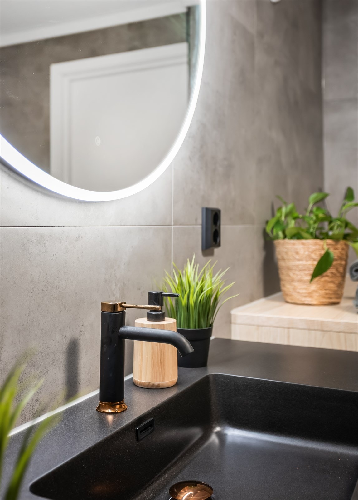 Servantskap med stilrene fronter, sort vask og et elegant, belyst speil. Galleribilde