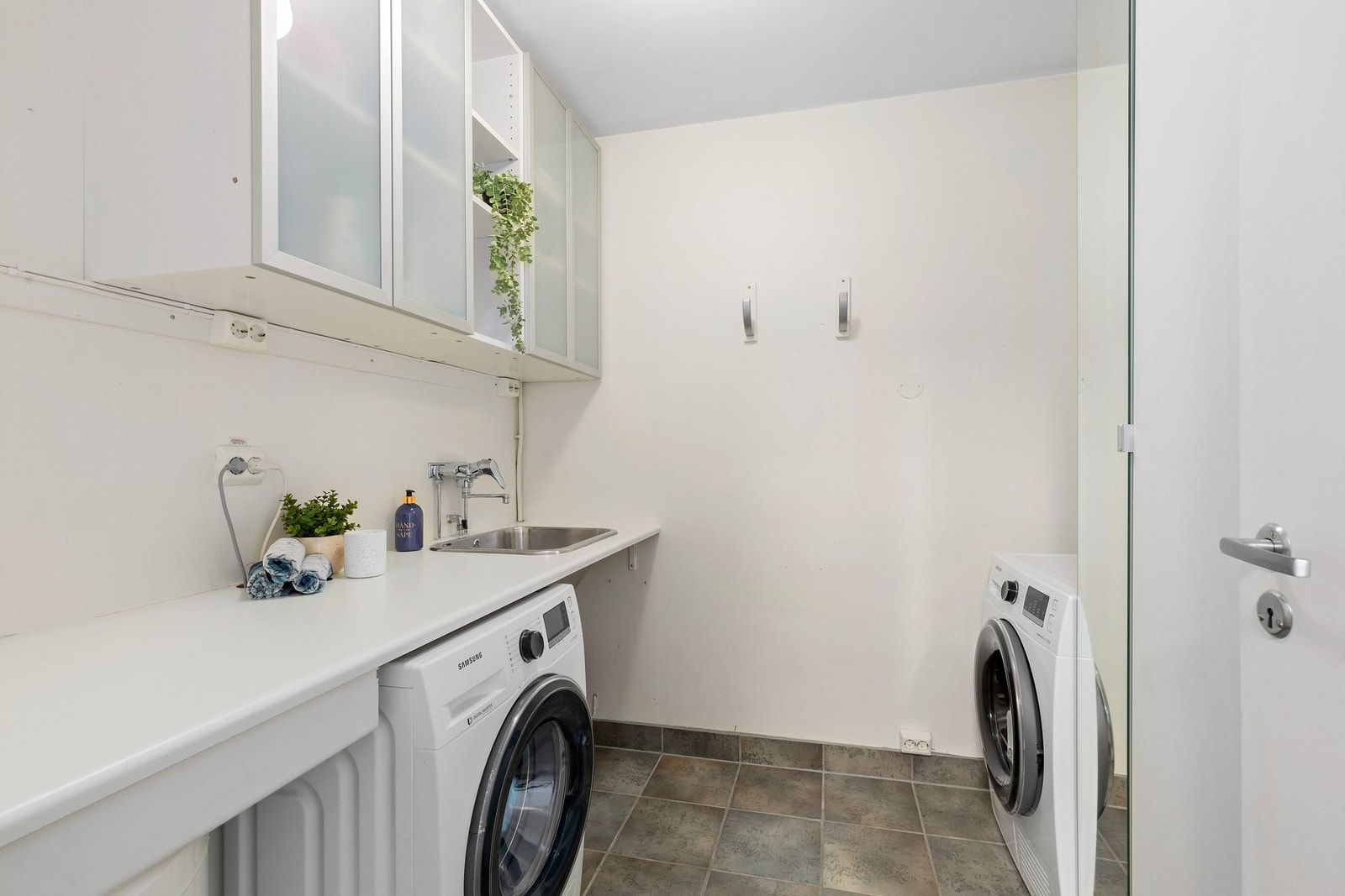 Praktisk vaskerom med opplegg for vaskemaskin, tørketrommel, og vask. Rommet ligger praktisk plassert i tilknytning til entréen. Galleribilde