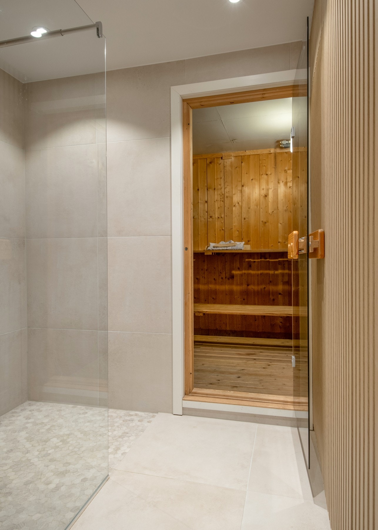 Fra badet er det direkte tilgang til boligens badstue med trepanel på vegger og himling - et perfekt sted for avslapning og velvære etter en lang dag. Galleribilde