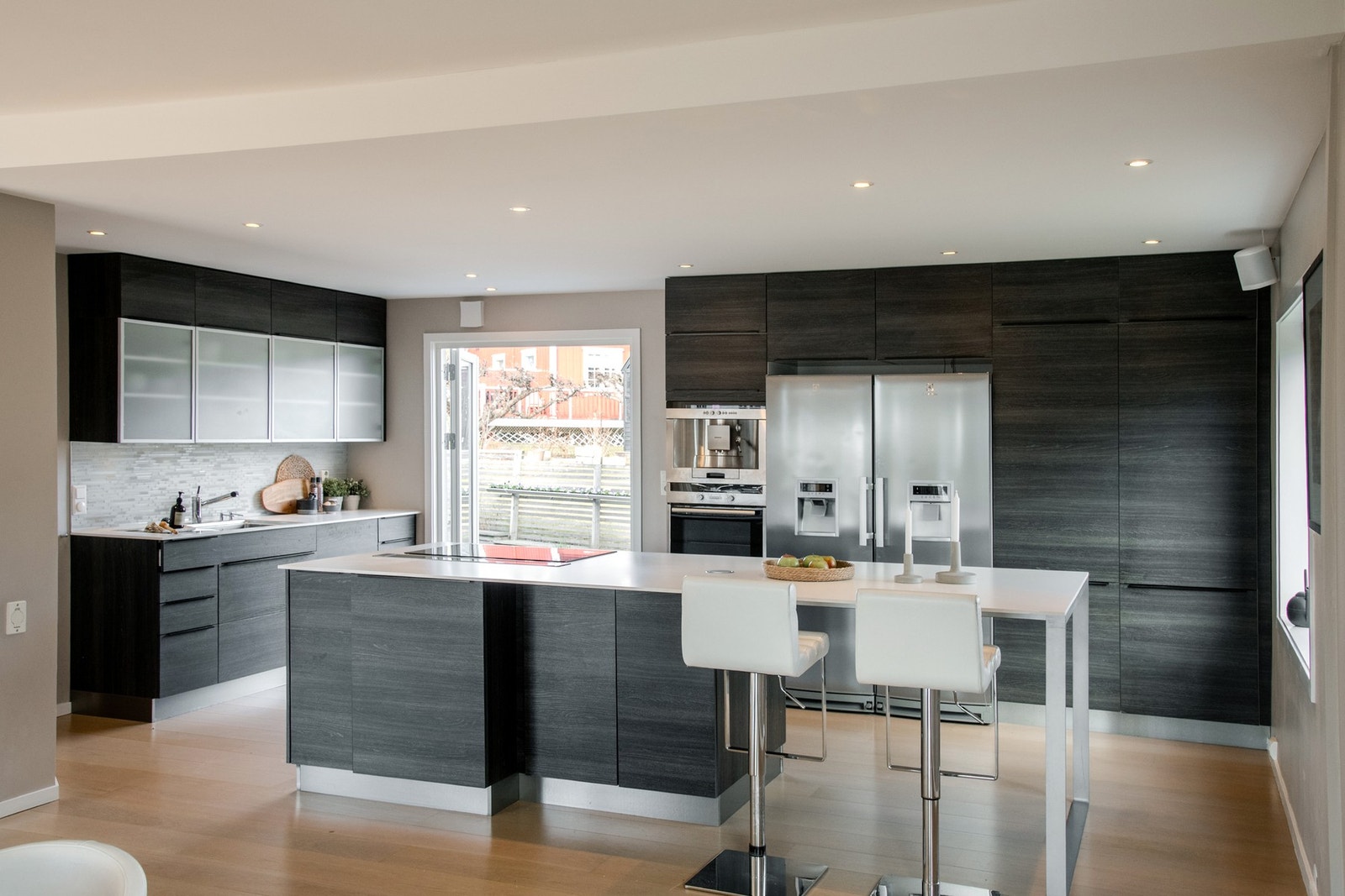 Stilrent og gjennomført kjøkken i åpen løsning mot spisestuen, utformet med fokus på både estetikk og brukervennlighet. Galleribilde