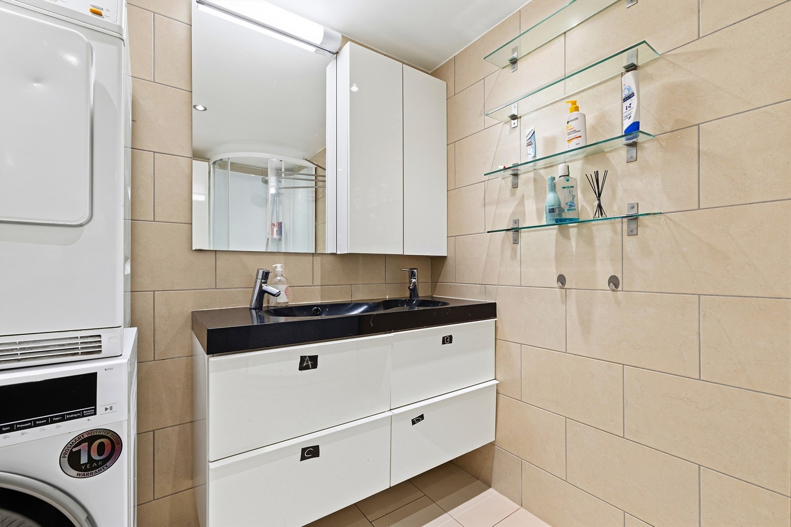 Flislagt bad med gulvvarme bestående av servant, dusjkabinett, toalett og opplegg for vaskemaskin. Galleribilde