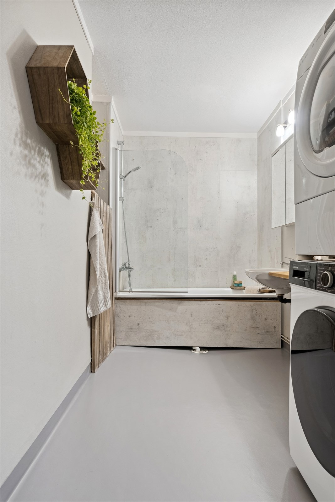 Her finner du badekar m/dusjgarnityr på vegg, servant med speilskap over og opplegg for vaskemaskin/tørketrommel Galleribilde