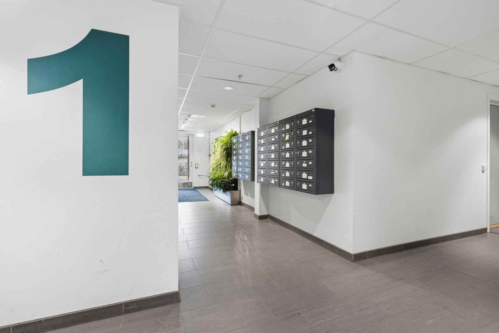 Pent og innbydende inngangsparti med postbokser og kameraovervåkning. Galleribilde