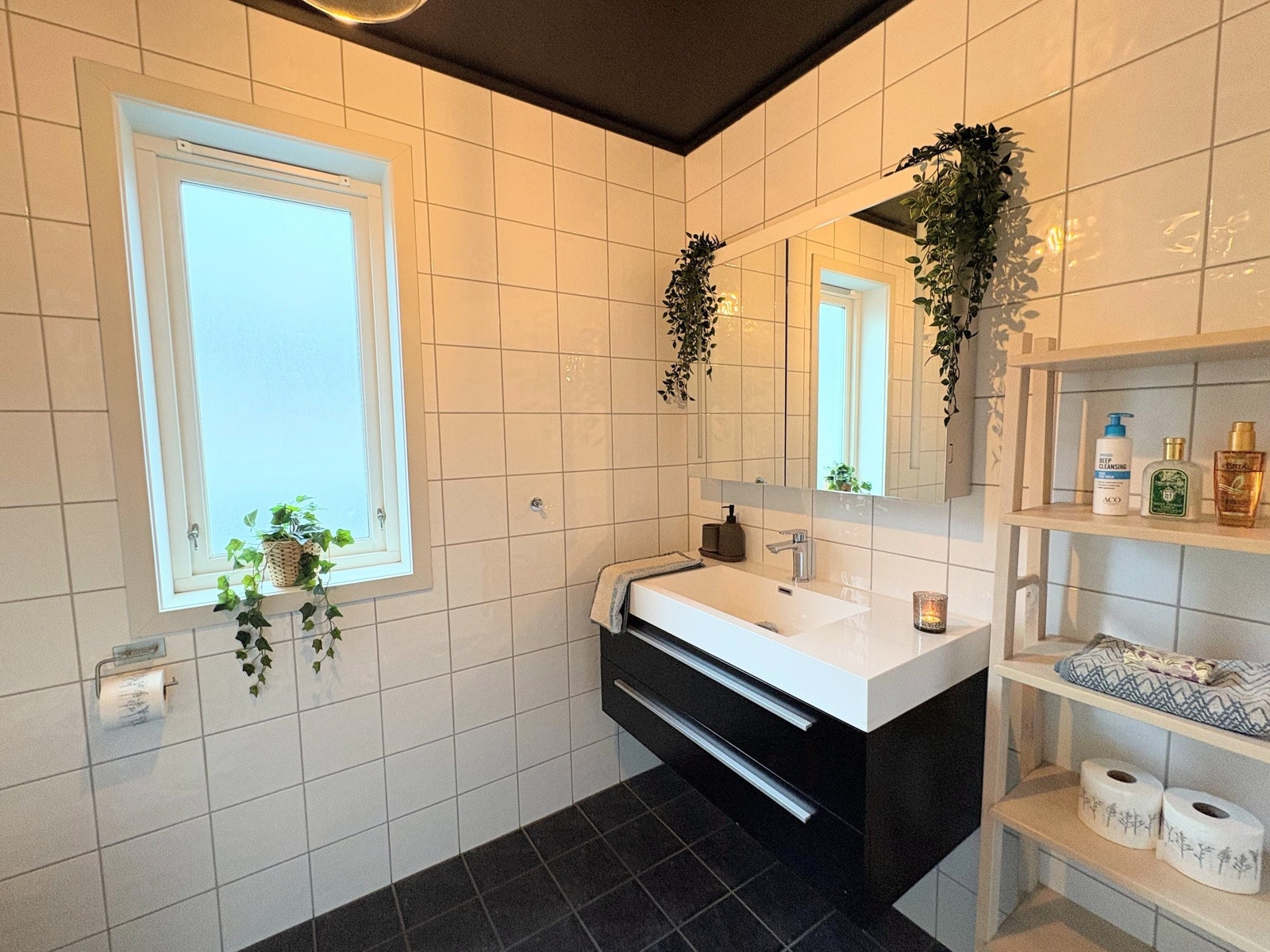 Flislagt bad med moderne servant og speil med innebygde lys både utvendig og innvendig Galleribilde