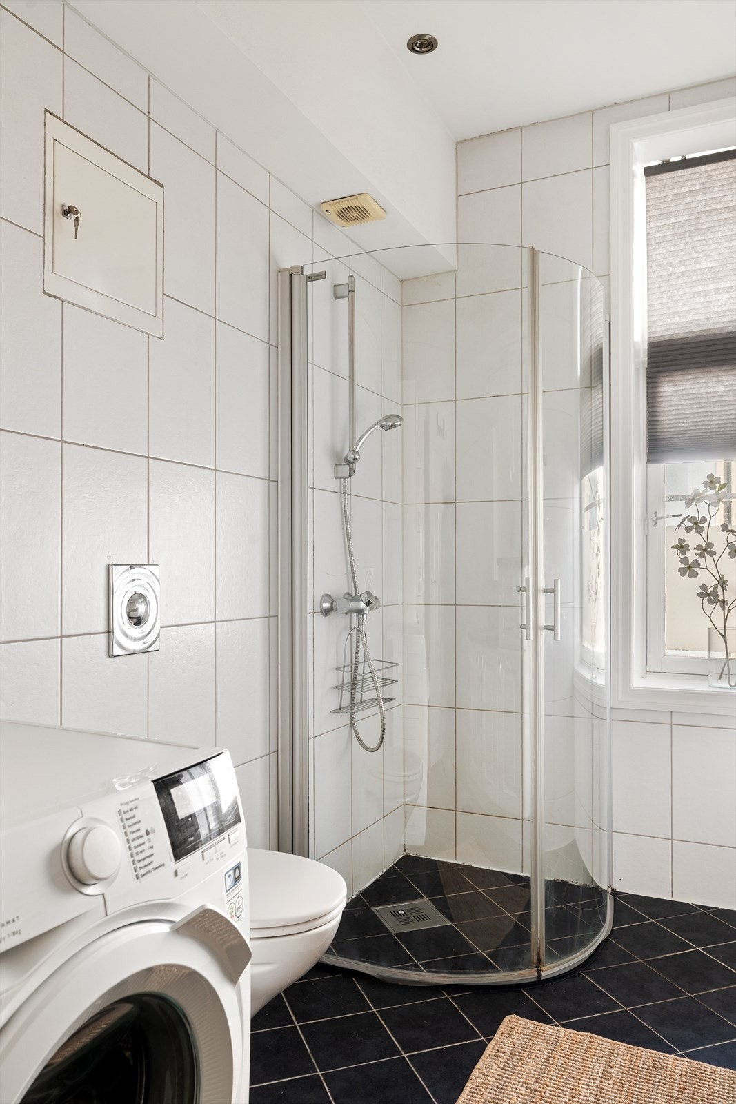 Videre er badet utstyrt med dusjhjørne, toalett, speil med tilhørende belysning, opplegg for vaskemaskin, downlights i himling og behagelig varme i gulv. Galleribilde