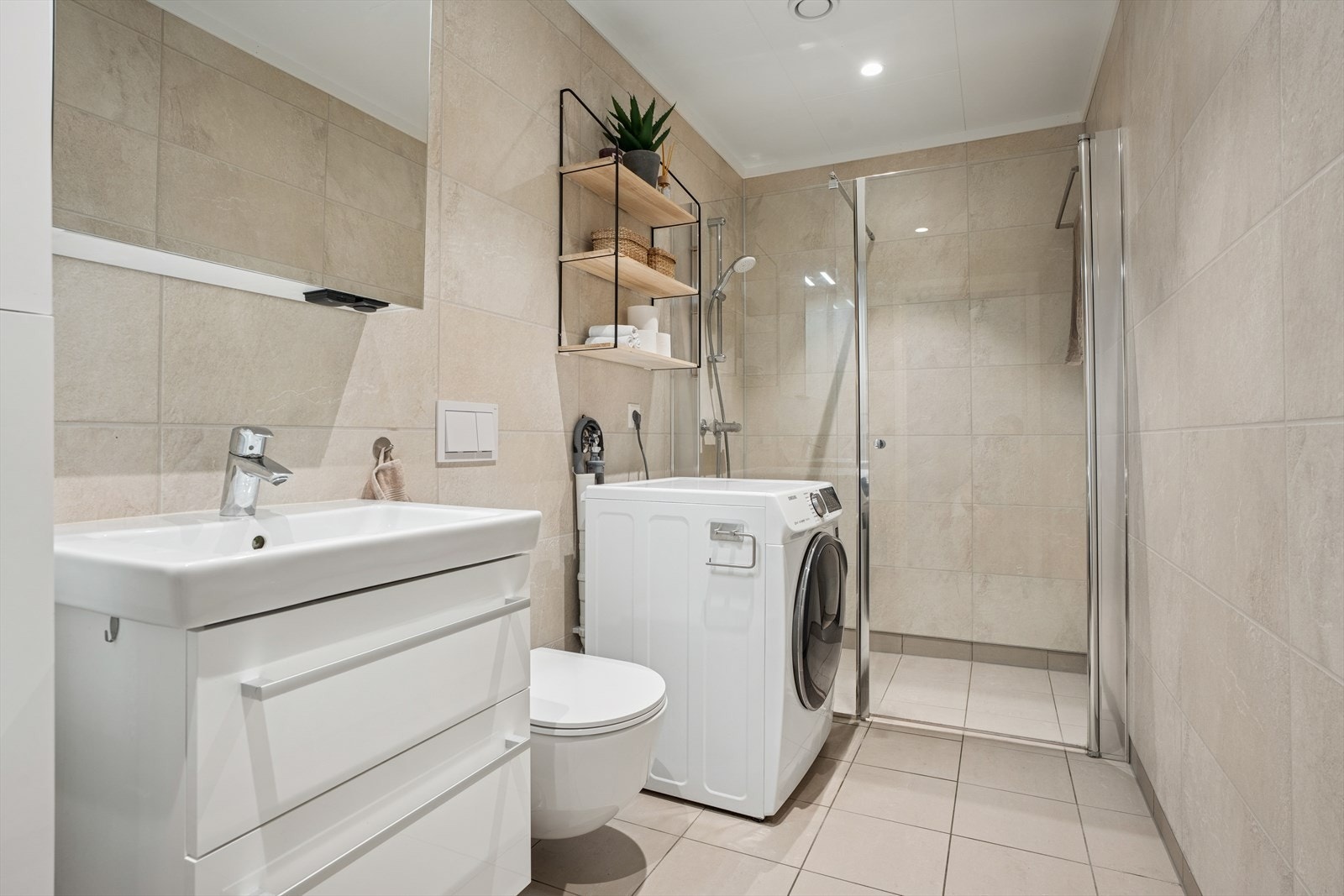 Lekkert baderom med våtromsplater på vegg og flislagt gulv med gulvvarme. Galleribilde