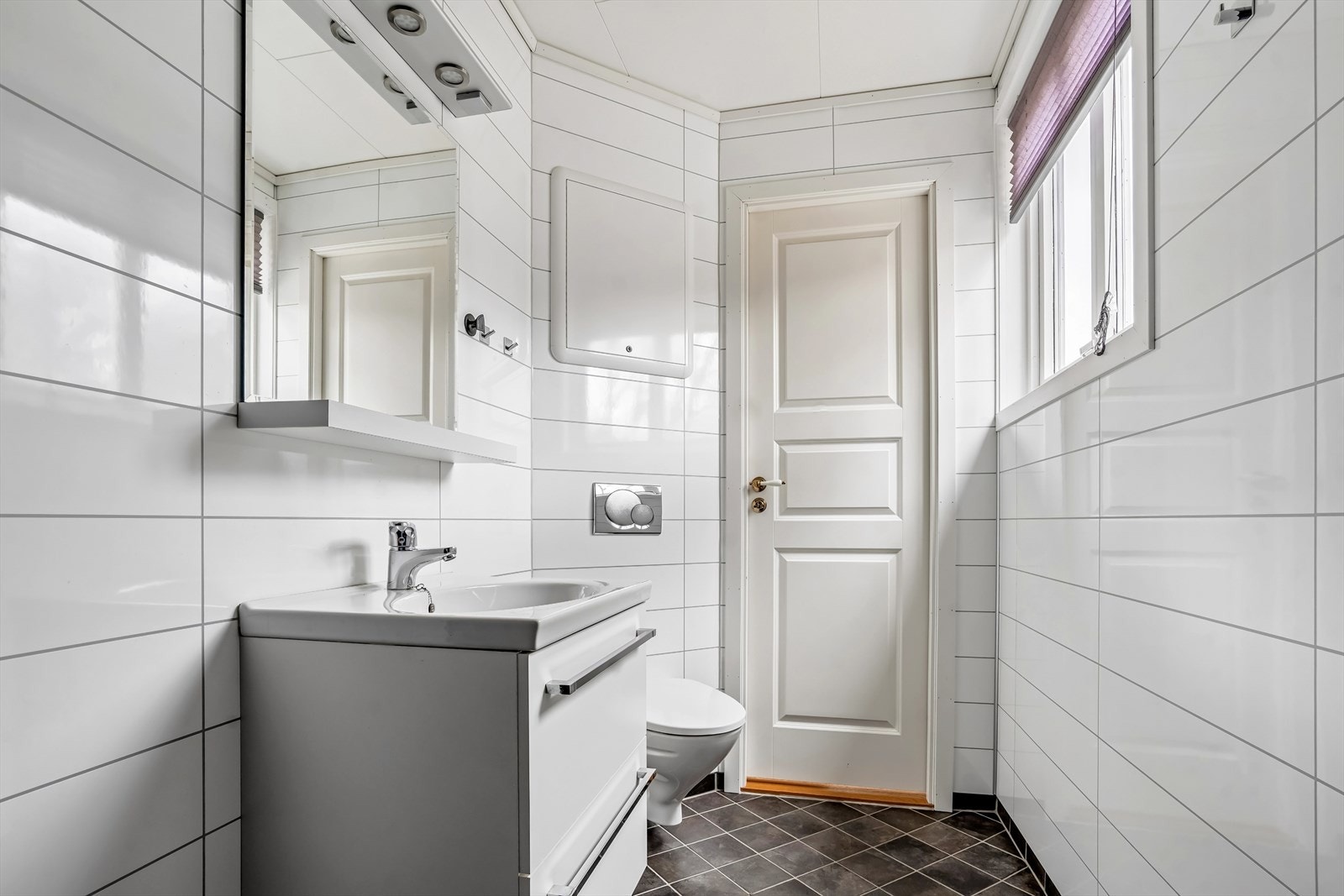 Badet er godt utnyttet og innredet med dusj, vegghengt wc, servant med skap og speil Galleribilde