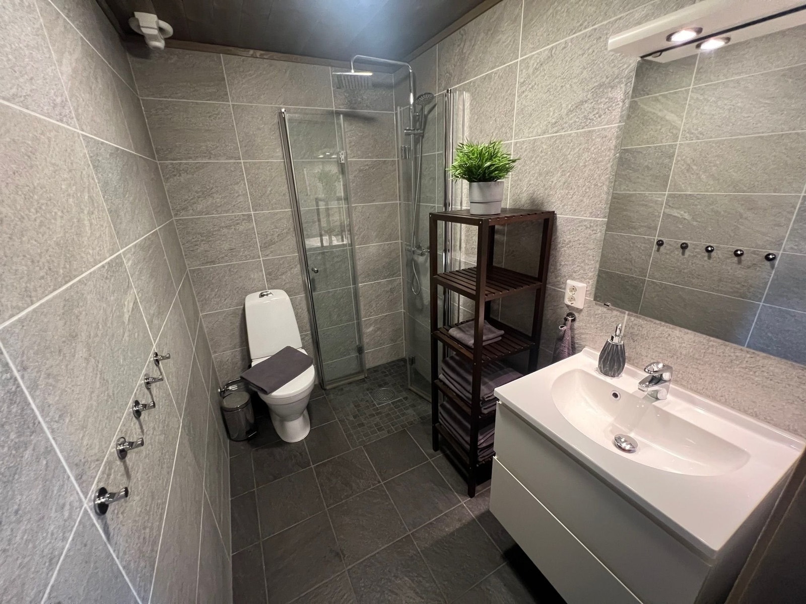 Praktisk baderom med varmekabler i gulvet. Dusjhjørne med regnfall og innfellbare dører. Galleribilde