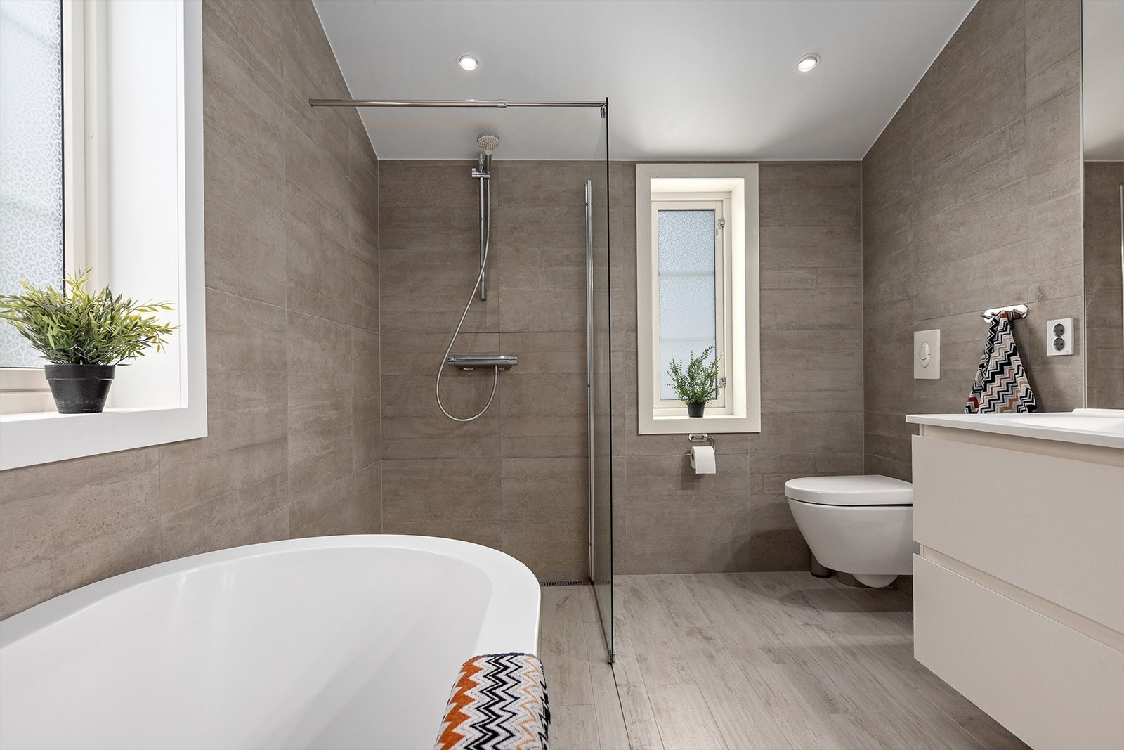 Vegghengt toalett og 2 vinduer på badet Galleribilde