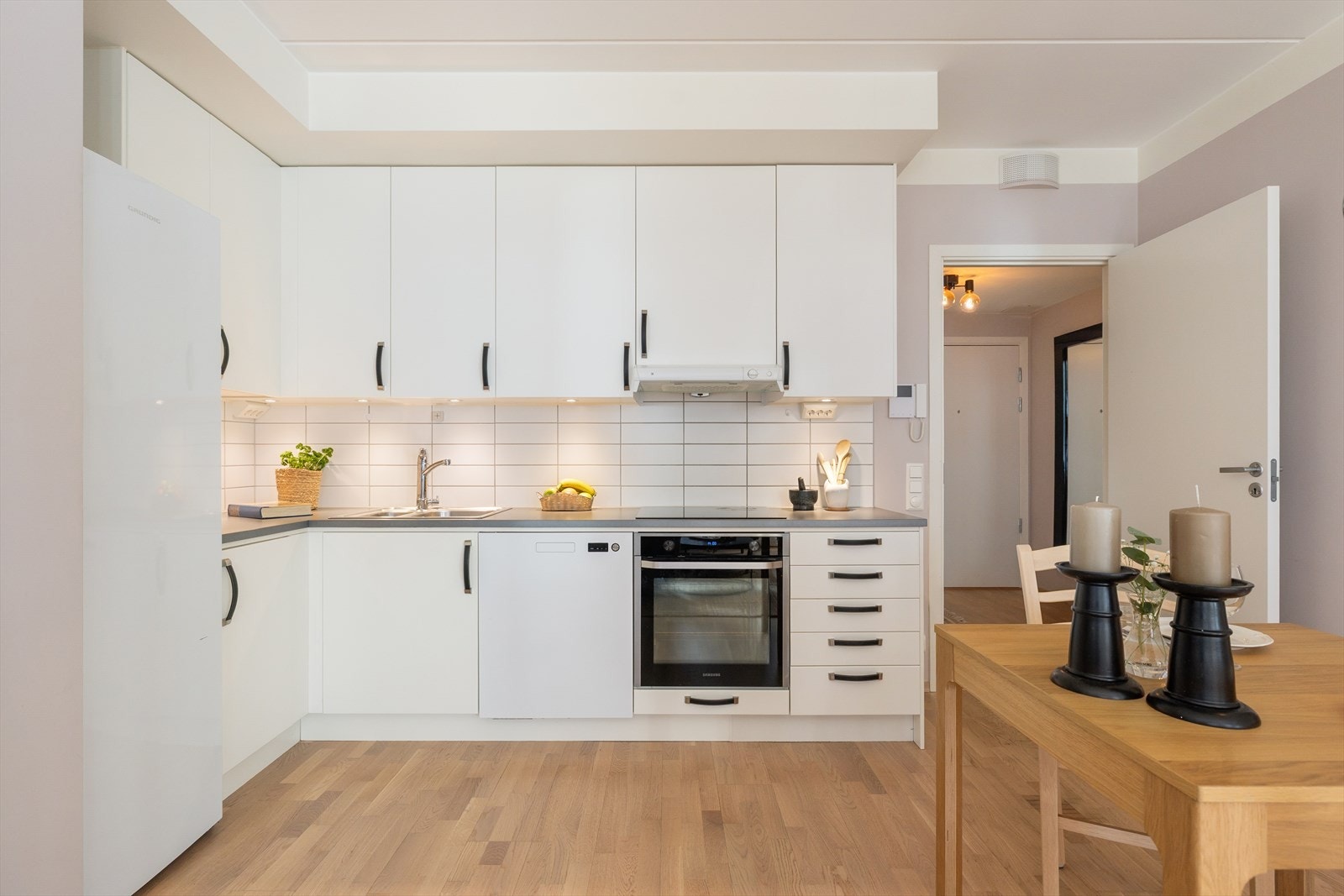 Kjøkkenet har laminert benkeplate, fliser mellom overskap og benk, kum med ettgreps blandebatteri, integrert koketopp og stekeovn med mekanisk vifte over, belysning under overskap og integrert oppvaskmaskin. Galleribilde