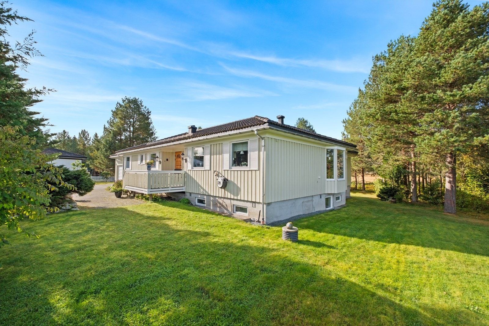 Huset er omkranset av pent opparbeidede uteområder med en kombinasjon av plen, naturtomt og stor gårdsplass. Galleribilde