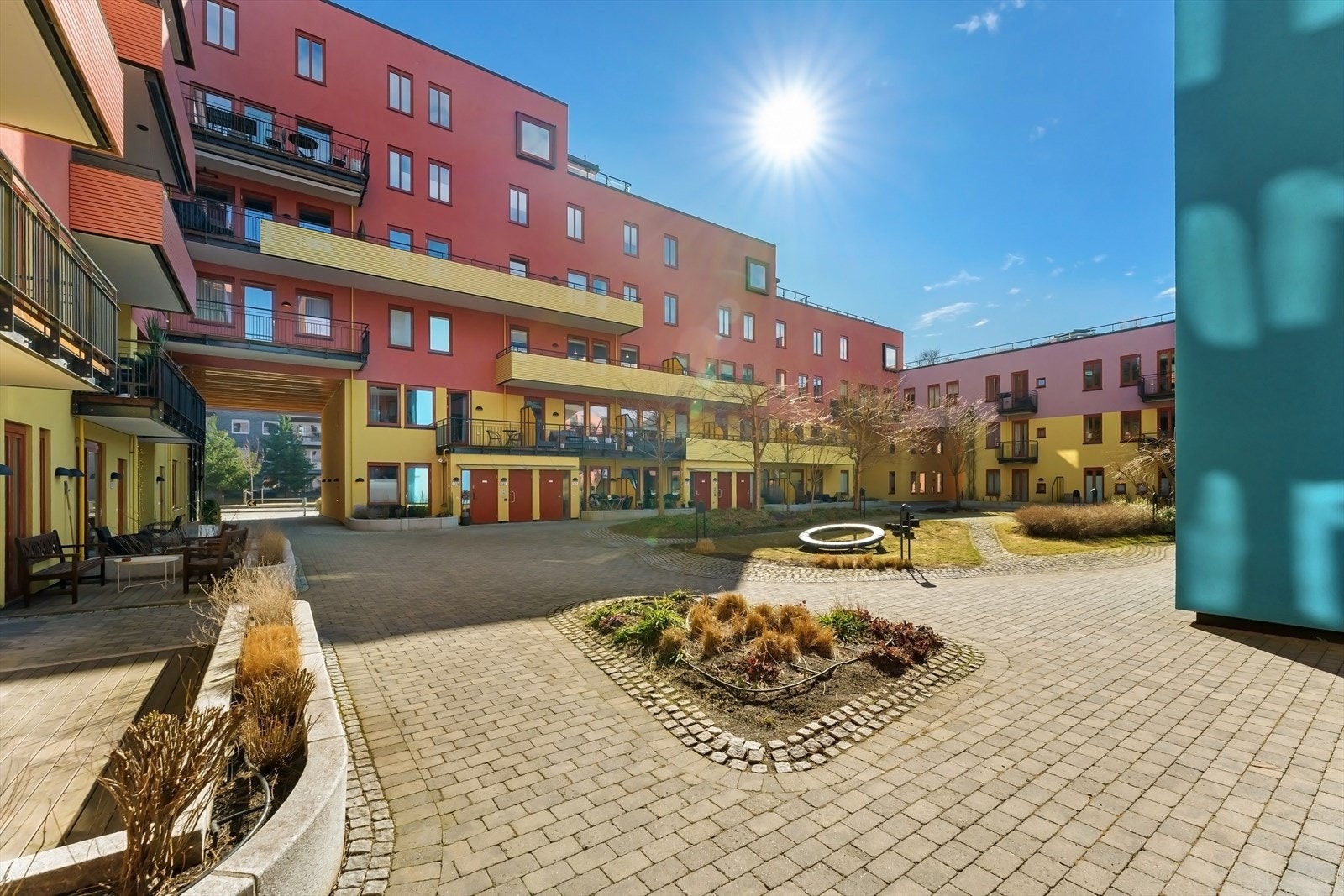 Hyggelig og pent opparbeidet gårdsrom med brostein, plen og beplantning. Galleribilde