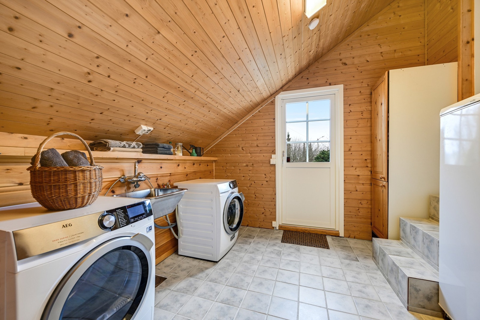 Romslig vaskerom med plass til både vaskemaskin og tørketrommel. Flislagt gulv og utgang til en hyggelig uteplass. Galleribilde