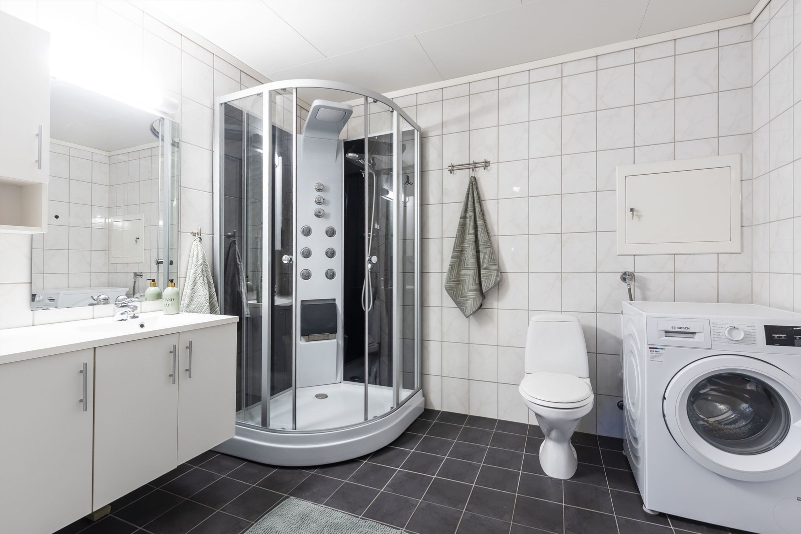 Stort bad med nyere dusjkabinett, toalett, servantinnredning med skap og opplegg til vaskemaskin. Vaskemaskin kan medfølge. Galleribilde