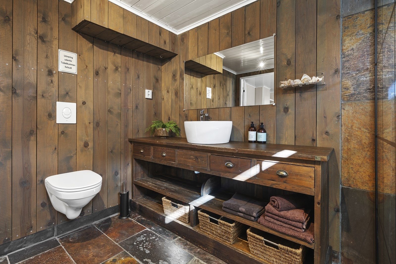 Baderommet er innredet med badekar, med vegghengt dusjgarnityr og dekorativ glassvegg Galleribilde