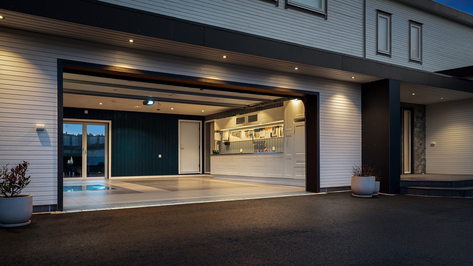 Drømmegarasje med kjøkkeninnredning og flotte fliser på gulv. Spotter i tak og direkteadkomst til bolighus via sluse. Galleribilde